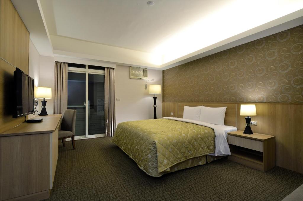 Habitación de hotel con cama y TV en Hoya Resort Hotel Chiayi en Minxiong
