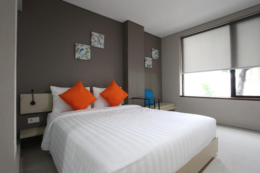 a bedroom with a large white bed with orange pillows at Wanadu Residence in Tangerang
