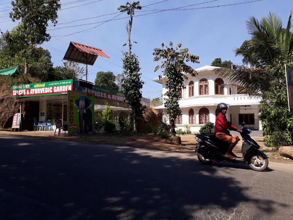 a man riding a motorcycle down the street at alhind Residency in Munnar