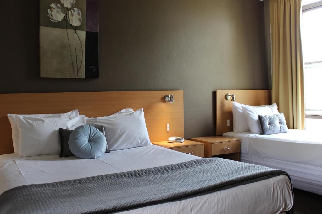 ein Hotelzimmer mit 2 Betten und einem Fenster in der Unterkunft El Toro Motor Inn in Warwick Farm