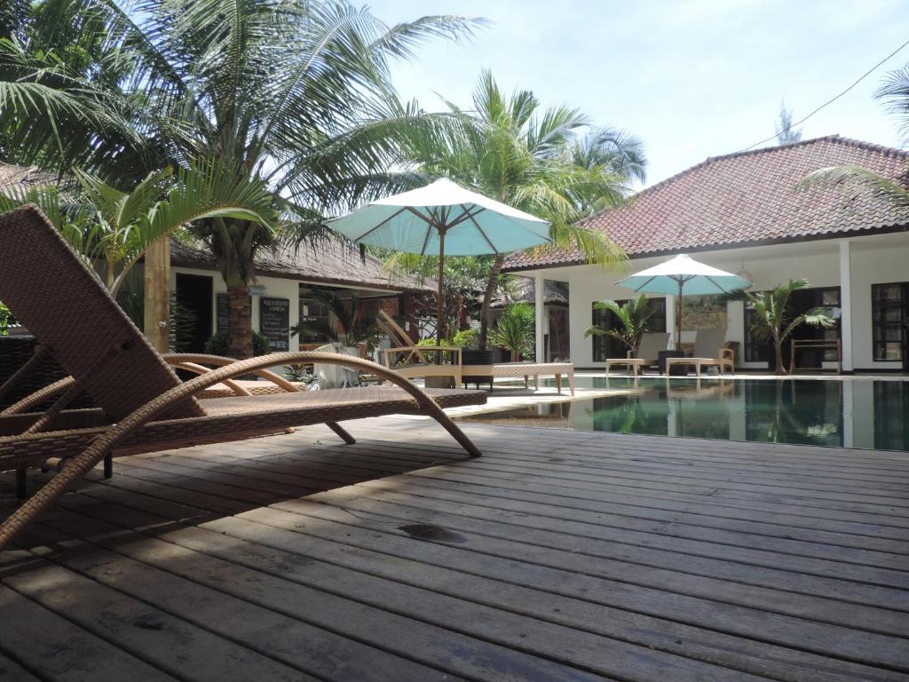 a deck with chairs and umbrellas next to a pool at Casus Dream Hotel in Gili Trawangan