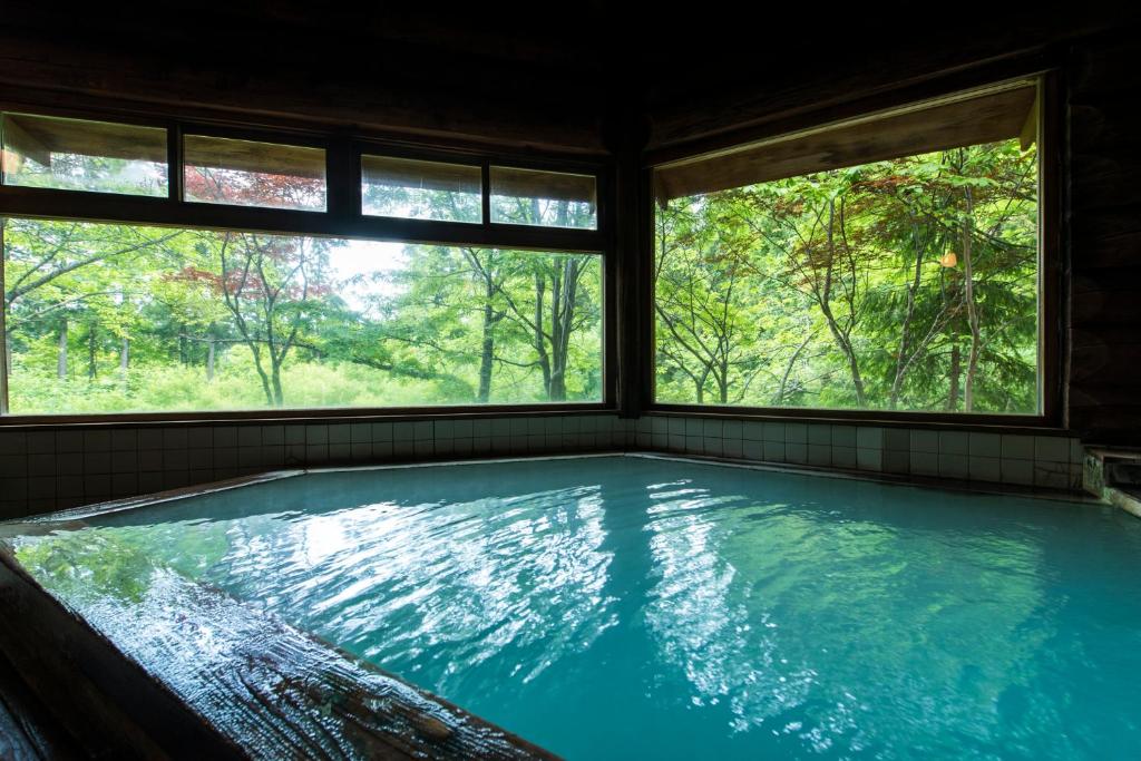 a large swimming pool in a room with two windows at Takamiya Hotel Hammond in Zaō Onsen