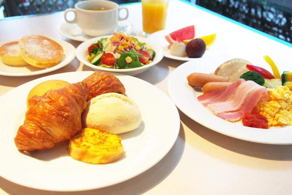 a table with plates of breakfast foods and a cup of coffee at New Otani Inn Tokyo in Tokyo