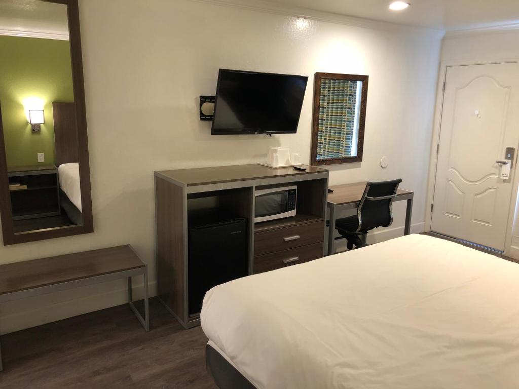 a hotel room with a bed and a flat screen tv at Gilroy Inn in Gilroy