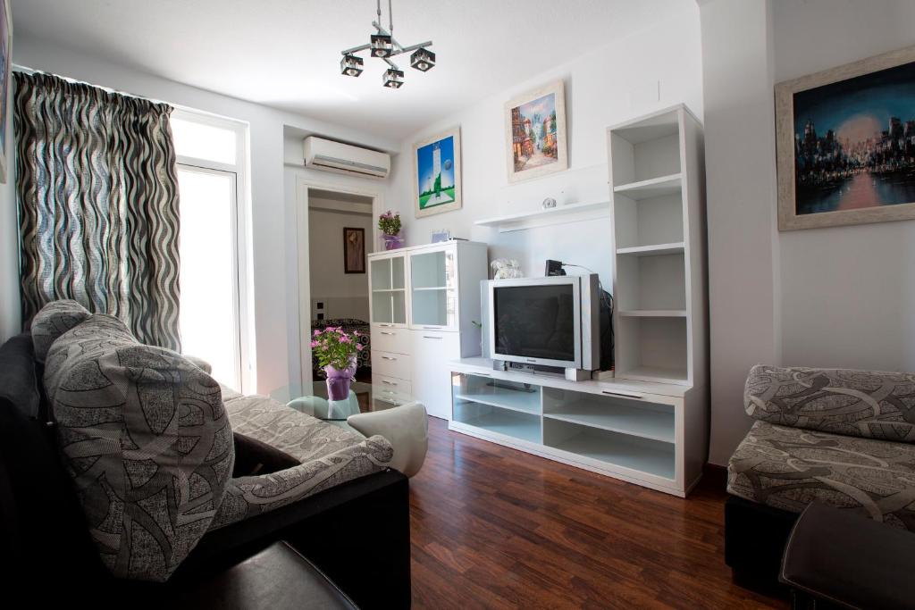 a living room with a television and a chair at Hotel Molinos in Granada