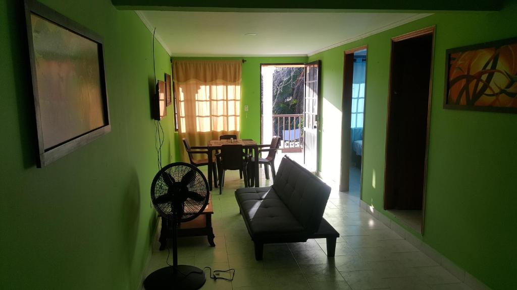 uma sala de estar com paredes verdes, uma cadeira e uma mesa em Miss Leila em San Andrés