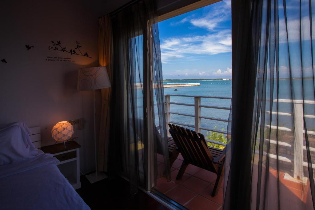 1 dormitorio con ventana y vistas al océano en Summer Ya B&B, en Huxi