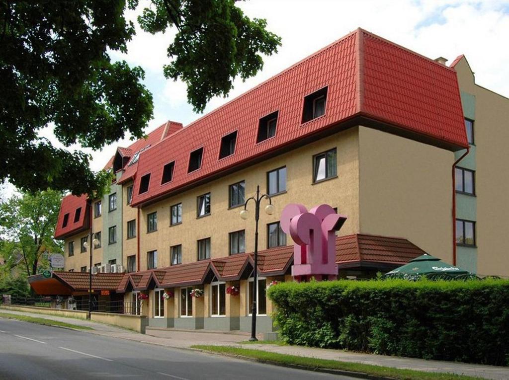 un bâtiment avec un toit rouge sur le côté d'une rue dans l'établissement Willa Wolność, à Polanica-Zdrój