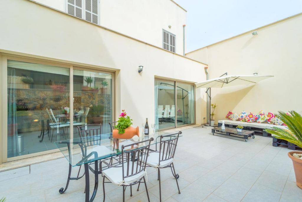 un patio con mesa de cristal y sillas en Casa Holganza, en Maria de la Salut