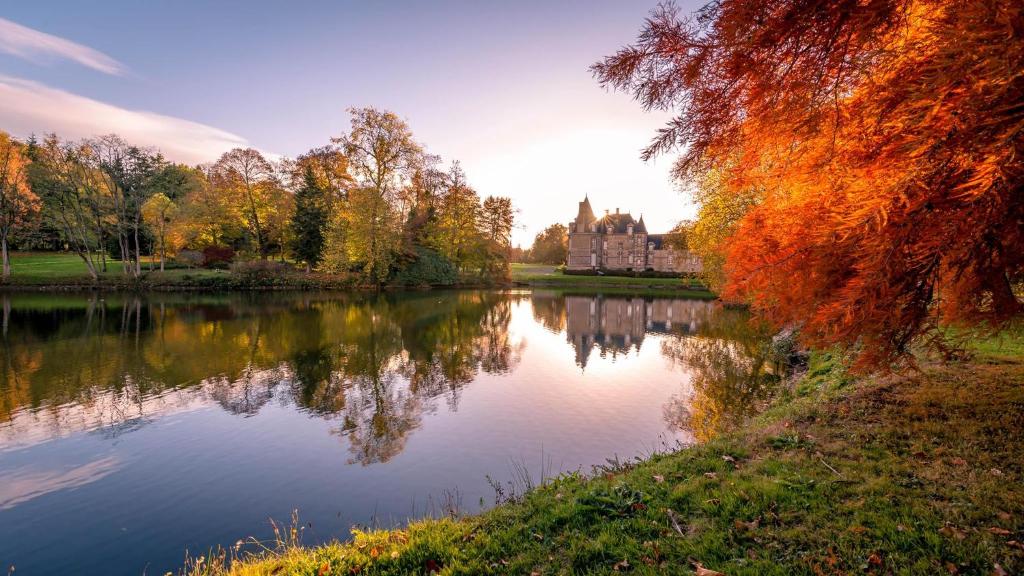 un castello si riflette nell'acqua di un lago di Chateau de Canisy a Canisy