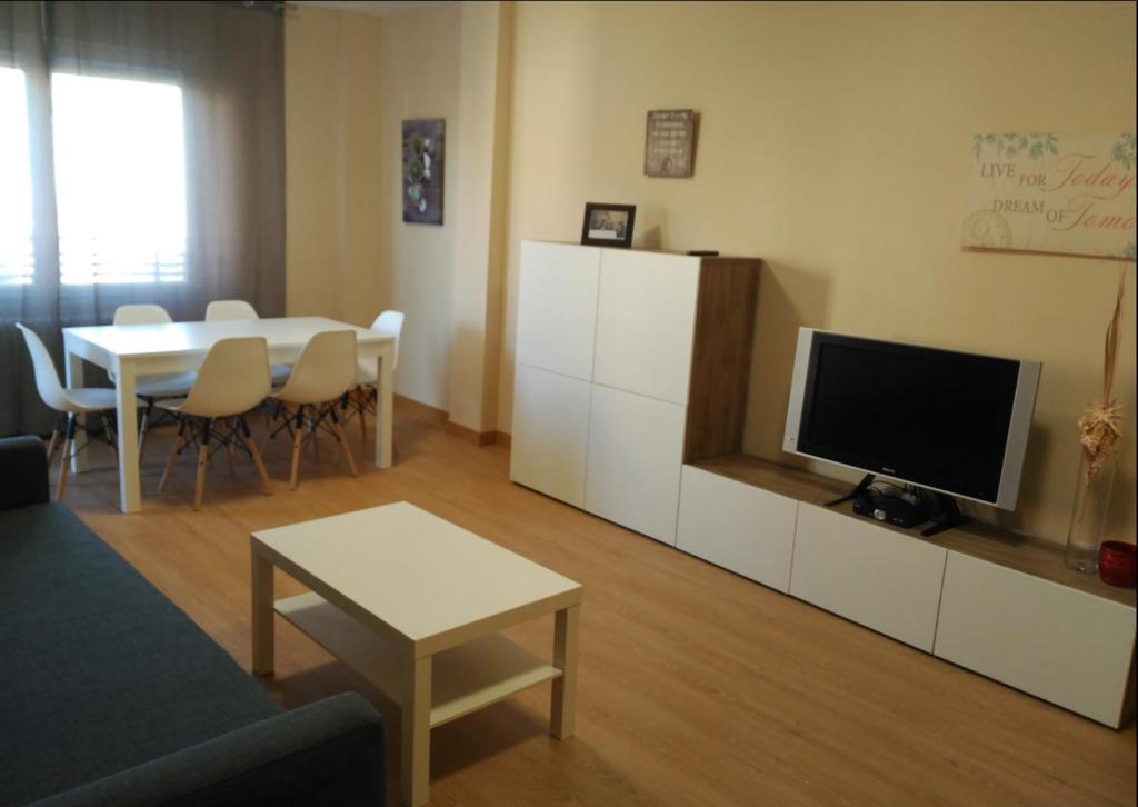 Zamora Apartments في سمورة: غرفة معيشة مع تلفزيون وطاولة مع كراسي