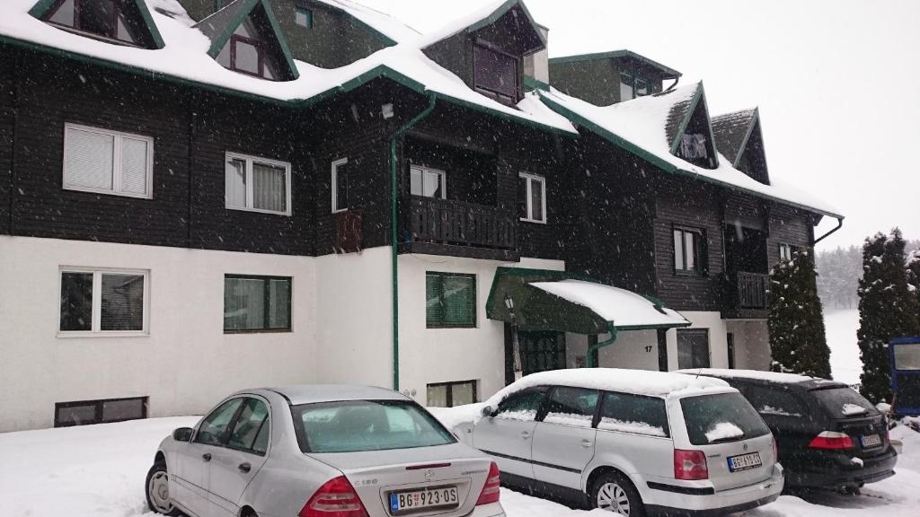 two cars parked in front of a building in the snow at Apartment Vukajlo Zlatibor in Zlatibor