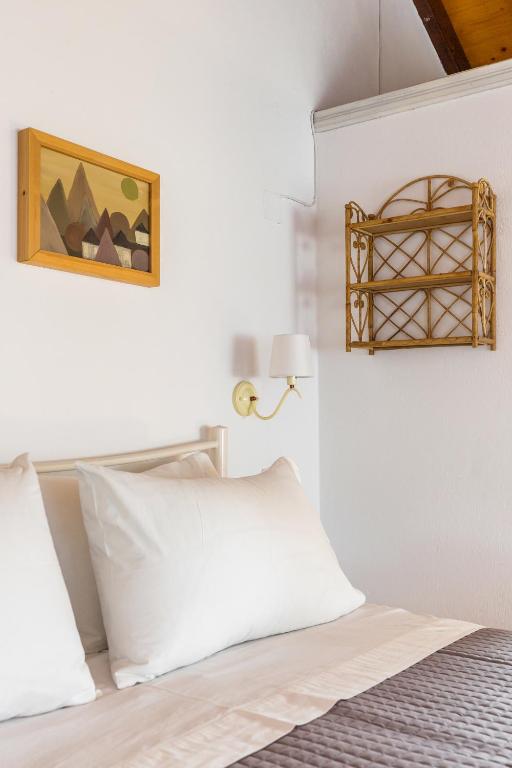 a white bedroom with a bed and a picture on the wall at Villa Thea in Panormos Skopelos