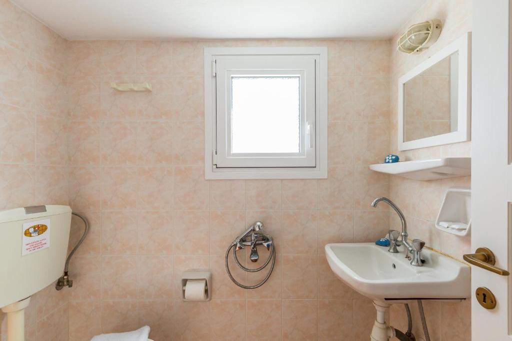 a bathroom with a sink and a toilet and a window at Villa Thea in Panormos Skopelos