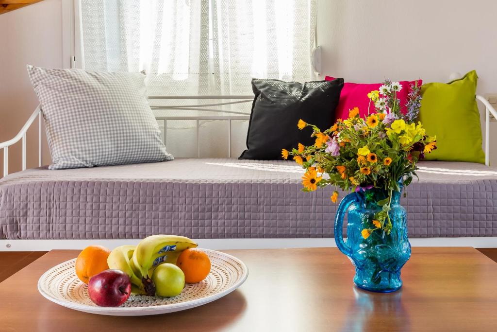 a table with a vase of flowers and a plate of fruit at Villa Thea in Panormos Skopelos