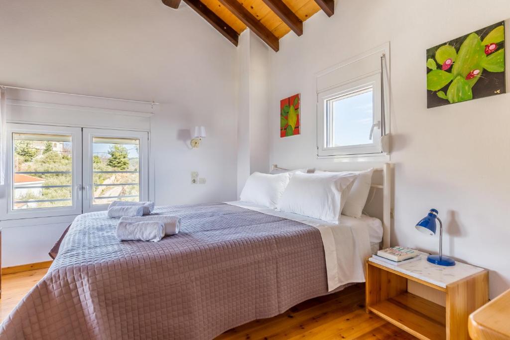 a white bedroom with a large bed and two windows at Villa Thea in Panormos Skopelos