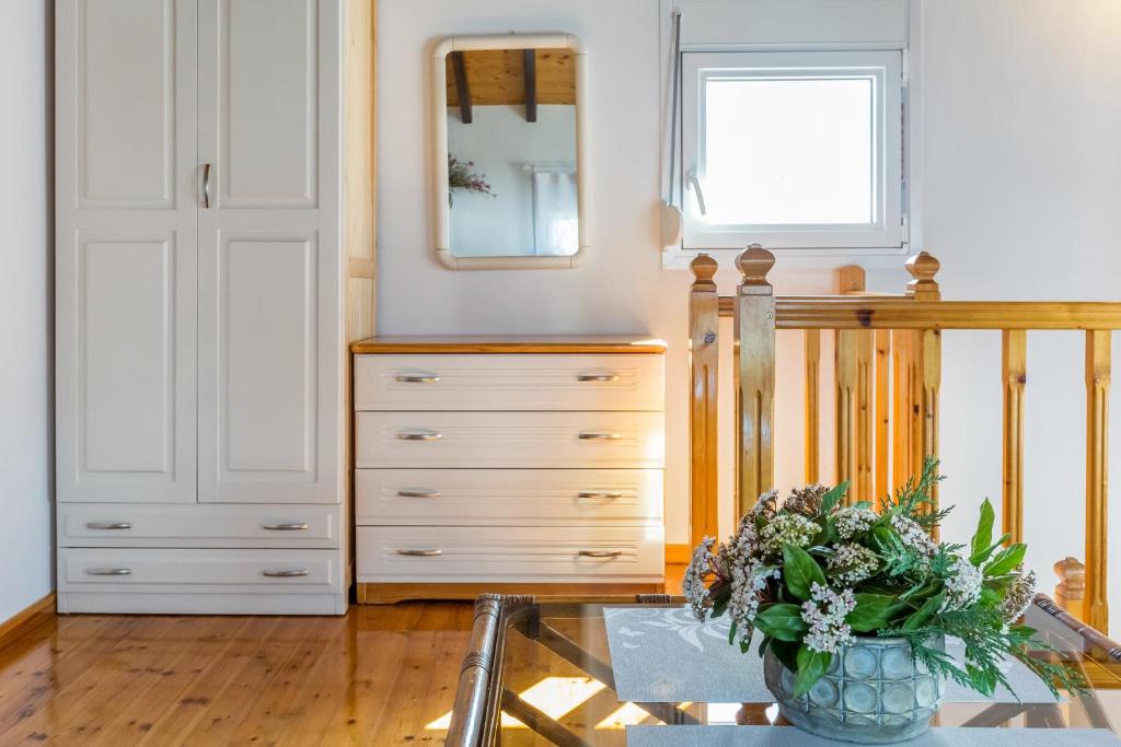 a room with a dresser and a vase of flowers at Villa Thea in Panormos Skopelos