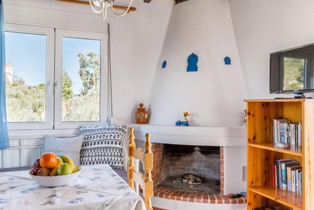a living room with a fireplace and a table with a bowl of fruit at Villa Thea in Panormos Skopelos