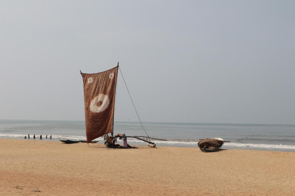 a flag on the beach with people in the ocean at Nethmi Rooms in Negombo