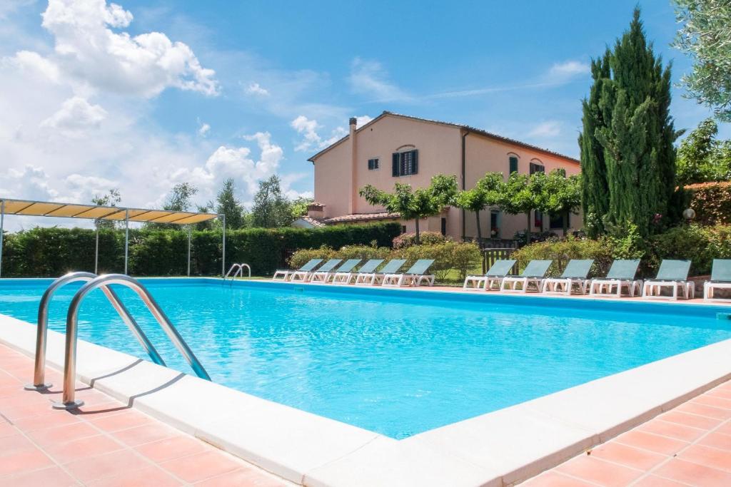 a swimming pool with chairs and a house in the background at La Torre Apartments in Pistoia