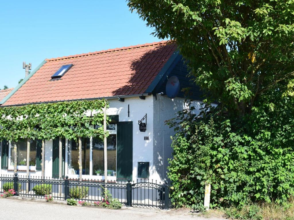 Casa blanca con techo rojo y valla en Comfortable holiday home in Schoondijke, en Schoondijke