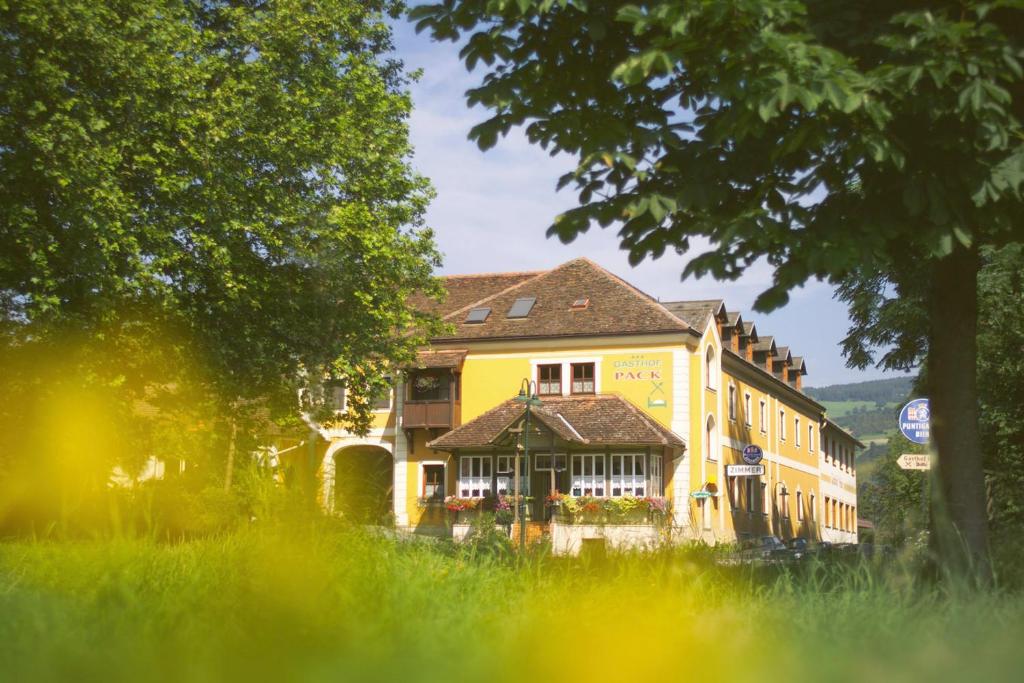 ein gelbes Gebäude in der Mitte eines Feldes in der Unterkunft Gasthof Pack "Zur Lebing Au" in Hartberg