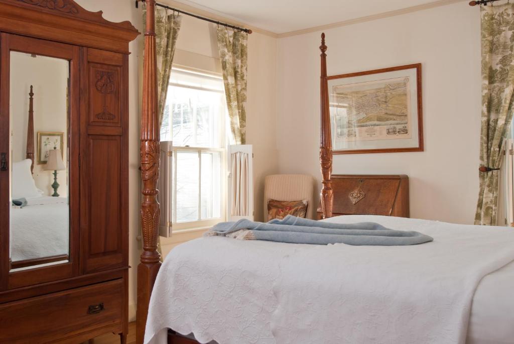 a bedroom with a bed with a dresser and a mirror at Marshall Slocum Inn in Newport