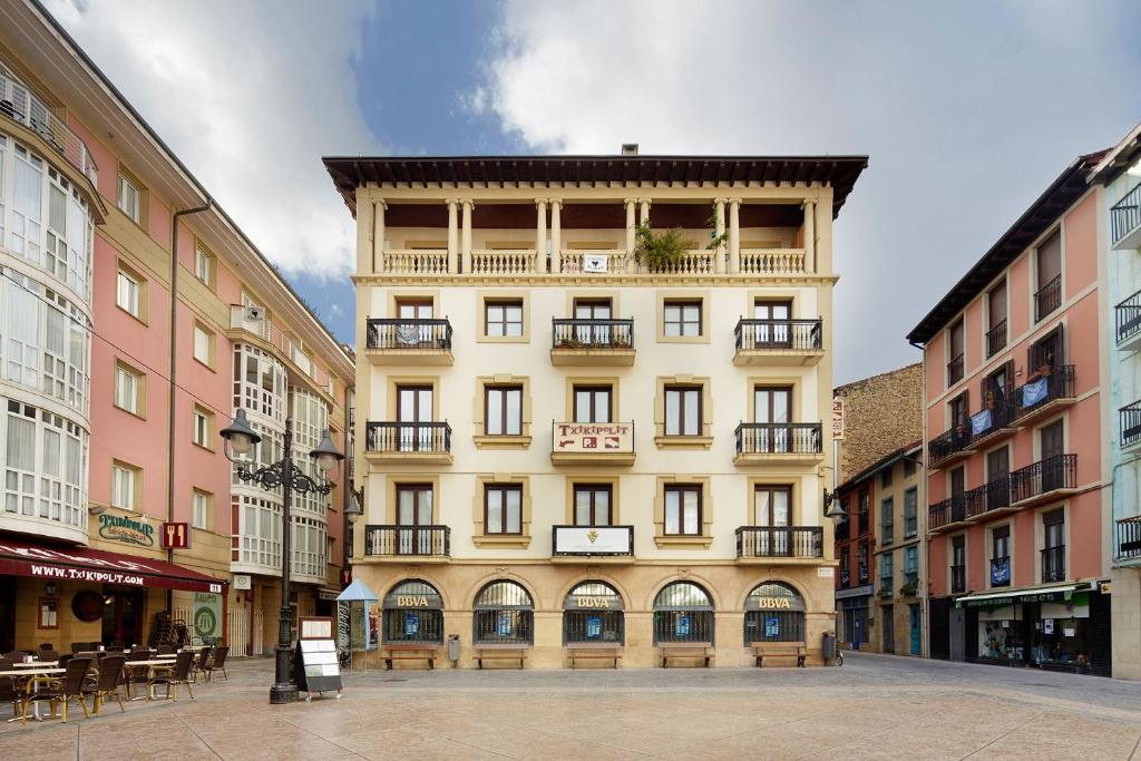 a tall yellow building with a balcony on a street at Musika Plaza in Zarautz