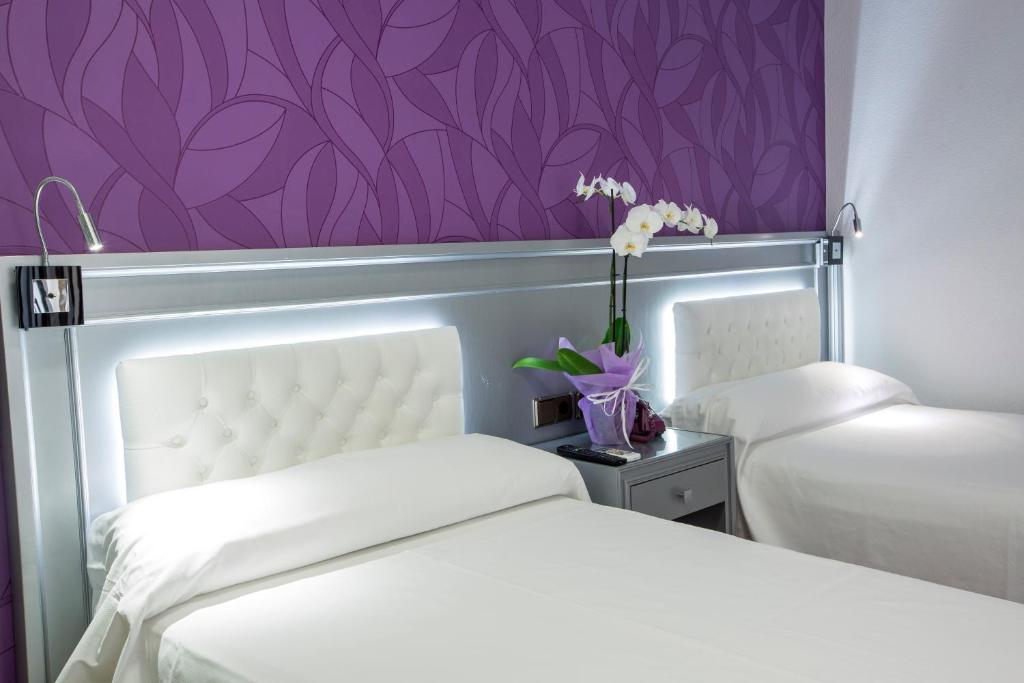 a bedroom with two beds and a purple wall at Hotel Molinos in Granada