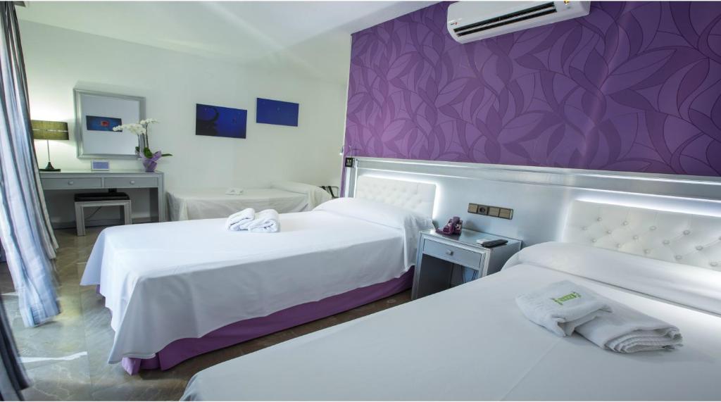 a hotel room with two beds and a purple wall at Hotel Molinos in Granada