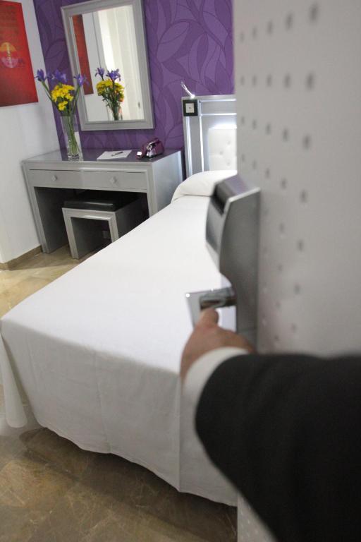 a bedroom with a white bed and a mirror at Hotel Molinos in Granada
