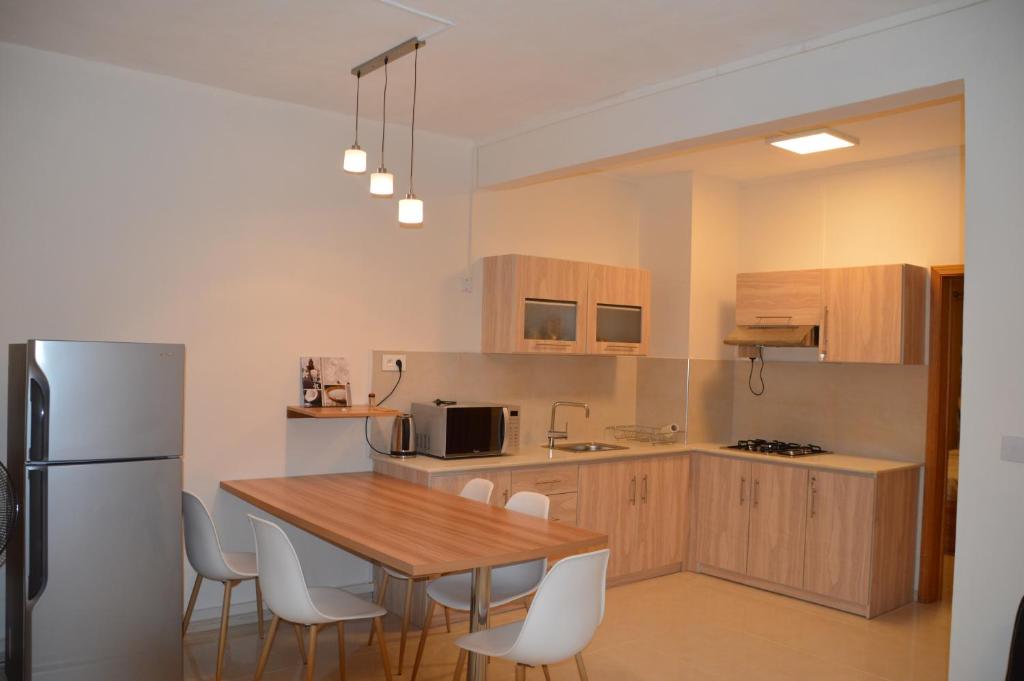 a kitchen with a wooden table and a refrigerator at AZ Pereybere Beach Apartment in Pereybere