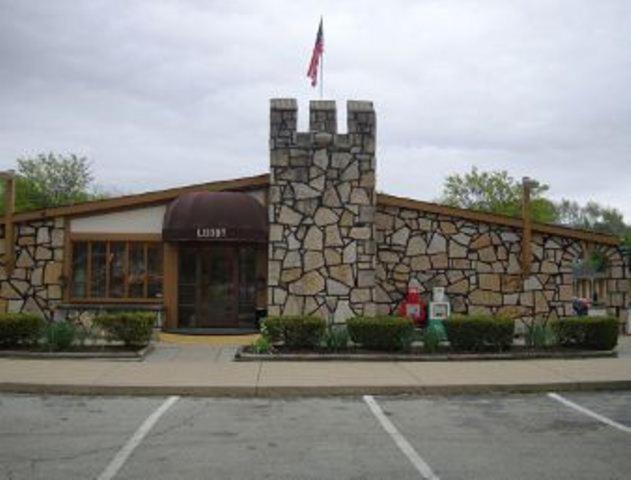 un edificio de piedra con una bandera delante de él en Knights Inn Greensburg, en Greensburg