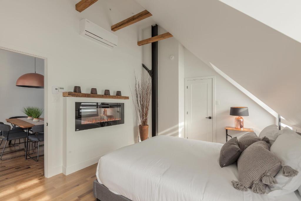 a bedroom with a white bed and a dining room at Les Lofts Ste-Anne in Quebec City