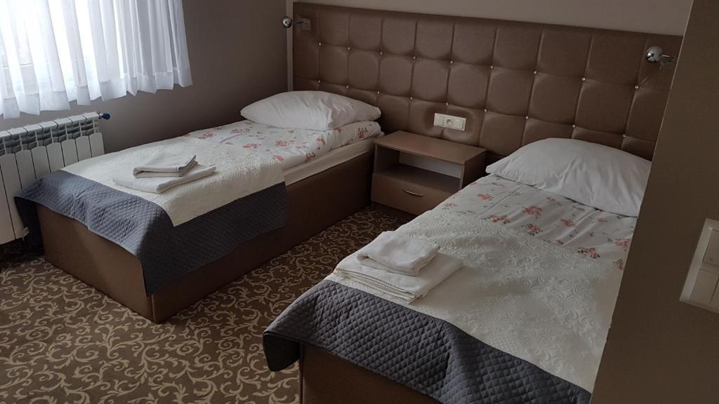 two beds in a small room with towels on them at Hotel Gutland in Wysokie Mazowieckie