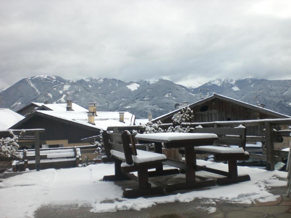 a snow covered picnic table with a view of mountains at Albergo Pensione Serenetta in Varena