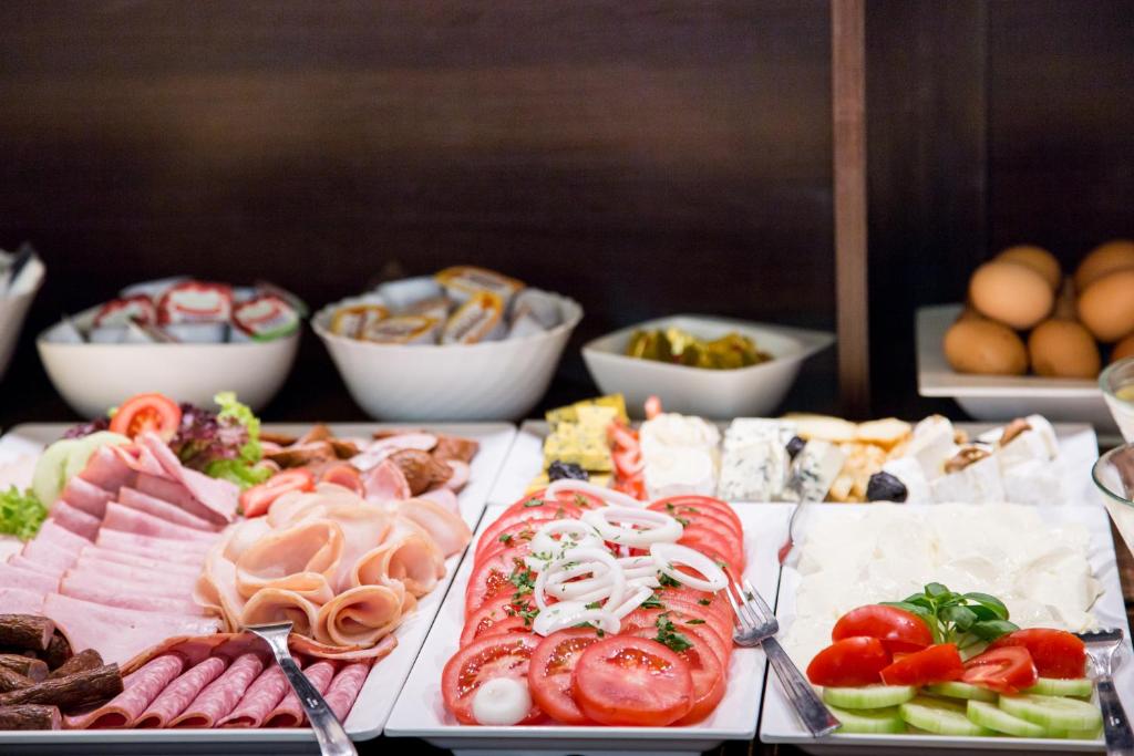 a buffet of food with meats and vegetables and eggs at Hotel Maksymilian in Krakow