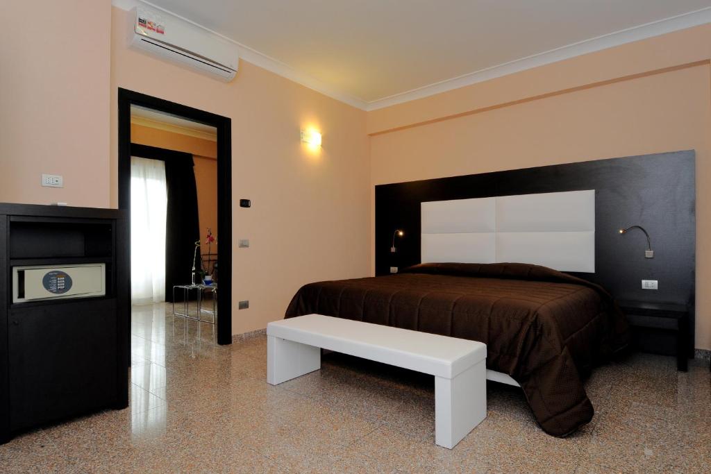 um quarto com uma cama grande e um banco branco em EH Suites Rome Airport Euro House Hotels em Fiumicino