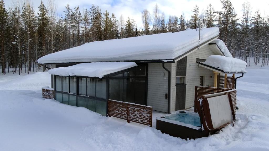 a house covered in snow in the woods at Lumikko Villa in Sonka