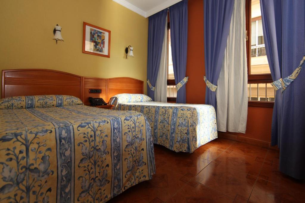 a hotel room with two beds and a window at Hostal Victoria in Málaga