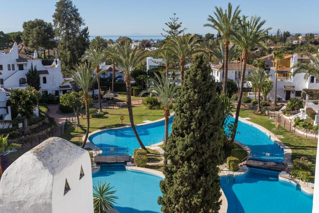 einen Luftblick auf einen Pool mit Palmen des Resorts in der Unterkunft Aldea Blanca Puerto Banus in Marbella