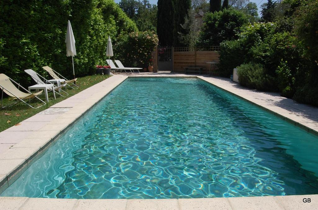 una piscina con sillas y sombrillas en un patio en Le Mas des Clots en Upie