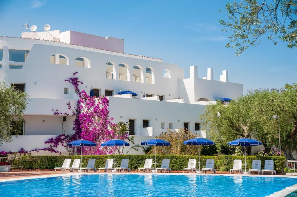 un hotel con una piscina con sillas y sombrillas en Hotel Torre Oliva, en Policastro Bussentino