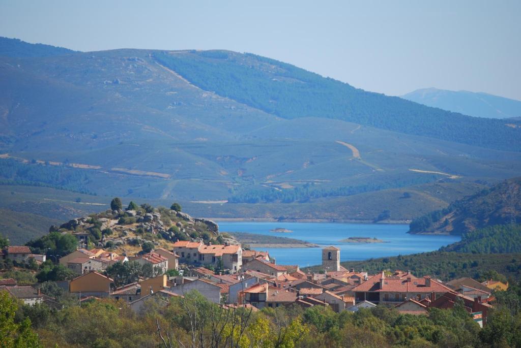 una pequeña ciudad en una colina con un lago en Alojamientos El Castillo en El Berrueco