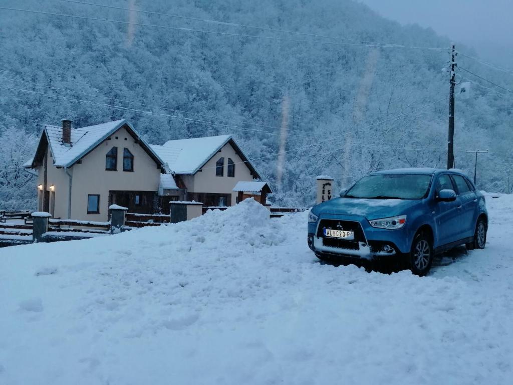 a blue car parked in the snow in front of a house at Lodge Zeleni svet in Crni Vrh