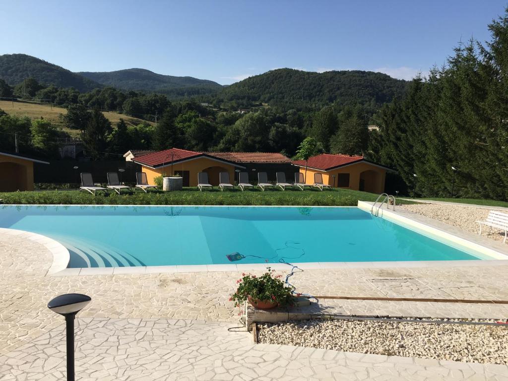 a large blue swimming pool with mountains in the background at villaggio casina del duca in Pescolanciano