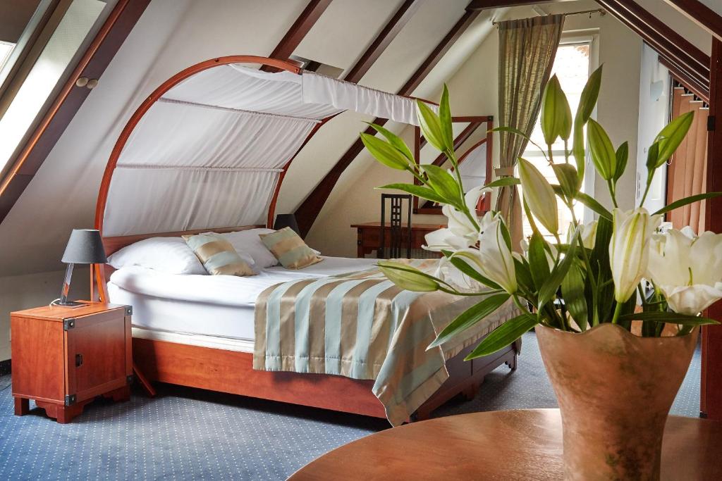 Un dormitorio con una cama y una mesa con una planta en Rezydencja Solei Old Town, en Poznan