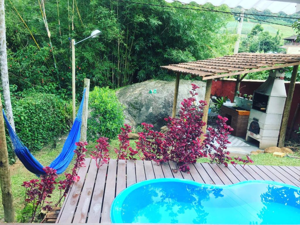 a hammock on a deck with flowers and a house at Casa Cravo & Canela in São Pedro da Serra
