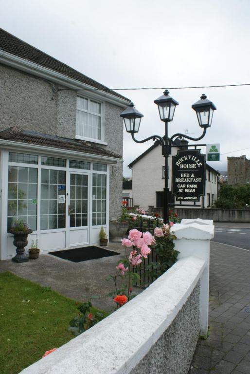 a building with a sign and flowers in front of it at Rockville House B&B in Cashel