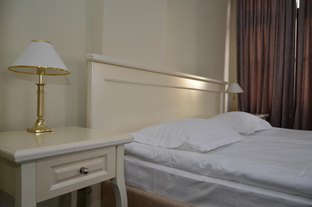 BerezovkaにあるChateau Royal Hotelのベッドルーム1室(ベッド1台、ランプ付きテーブル付)